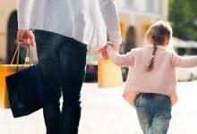 Young child in pink sweater holding her parents hand